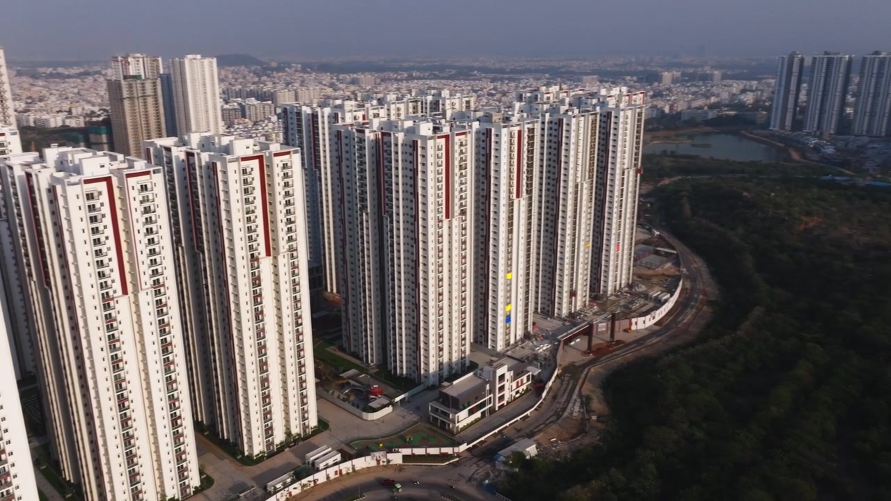 Apartamentos Aparna Zenon com Mushkin cheruvu, árvores, caixa d'água e a estrada de ligação Lanco Hills em Khajaguda, Narsingi, Hyderabad, Telangana, Índia. Imagem diurna, tomada em semicírculo, vista de drone, 4K.