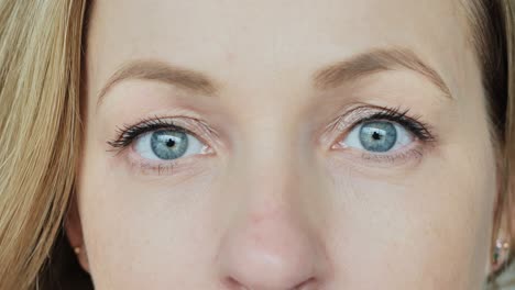 extreme close-up of woman calm blue eyes looking forward with slow motion focus