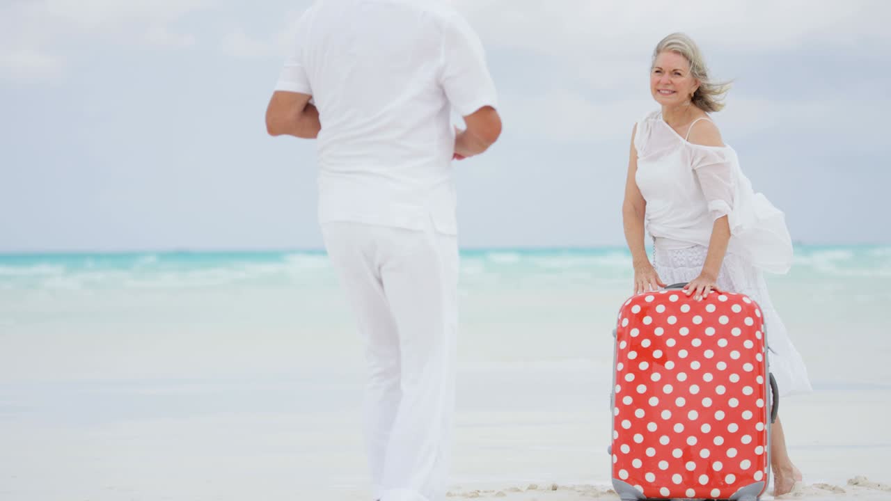 가방 과 카메라 를 들고 해변 에 있는 은퇴 한 부부