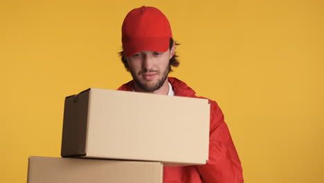 caucasian delivery man in front of camera on yellow background.