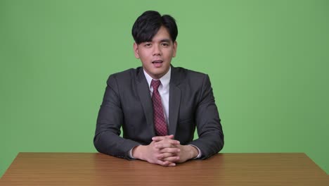 joven y guapo hombre de negocios asiático contra un fondo verde