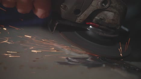 a slow-motion macro shot of a worker using an angle grinder to smooth a weld on sheet metal. bright sparks fly in a display of industrial metalwork and skilled craftsmanship