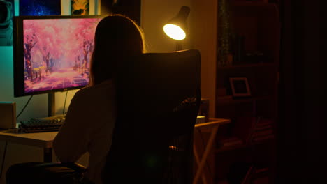 Woman Sitting at Desk Using Computer at Night