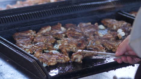 cerca de una persona asando pollo en una parrilla negra