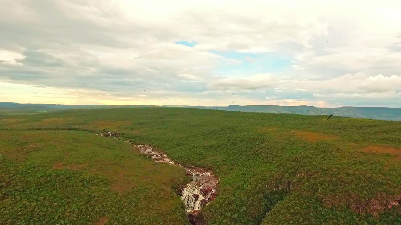 вид с высоты на водопад, стекающий с узкой реки в каньон