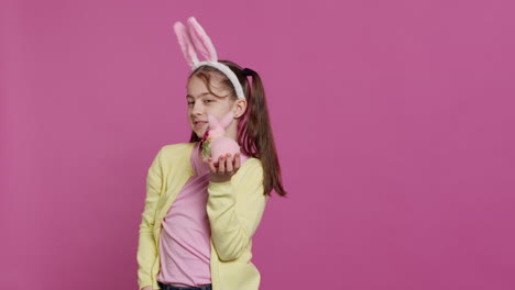 jolly schoolgirl holding a cute rabbit toy and blowing kisses in studio