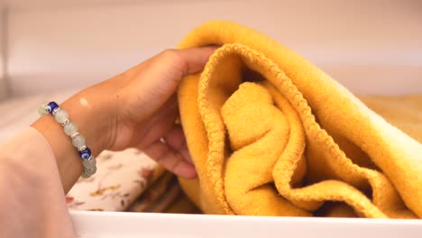 woman's hand reaching into a cabinet for a yellow blanket