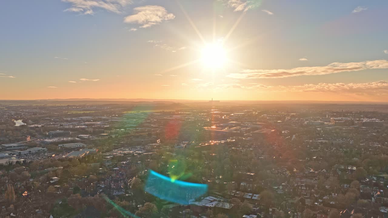 Nottingham by silhuet af gyldent solnedgangslys med fremtrædende turkis industribygning midt i kompositionen, omgivet af boligområder, grønne parker og nøgne vintertræer
