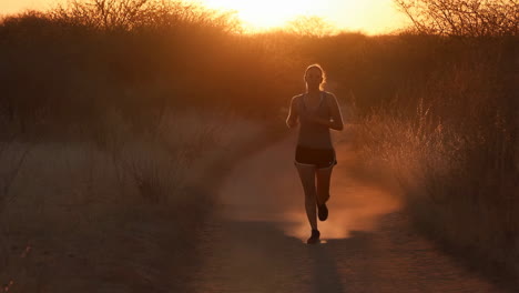 woman running on a trail at sunset