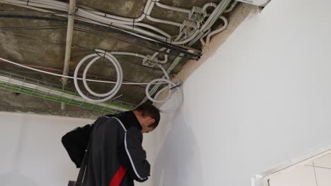 electricista inspeccionando cables y tuberías en el sitio de construcción