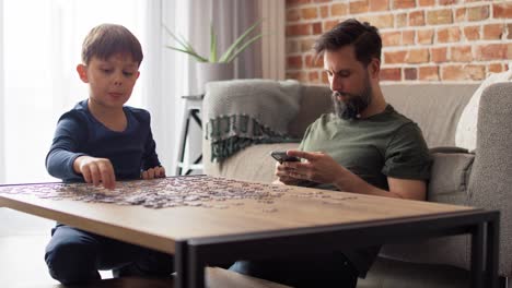 video von einem jungen, der ein puzzle löst, während der vater das telefon benutzt