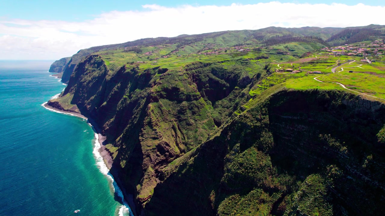 Zoom aéreo de drone capturando imponentes falésias vulcânicas, planaltos verdes e o profundo Oceano Atlântico azul ao longo da costa acidentada da Madeira
