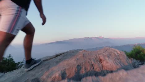 dramático vuelo bajo de drones entre árboles hacia el excursionista en el borde de la montaña y sobre el acantilado, en tiempo real