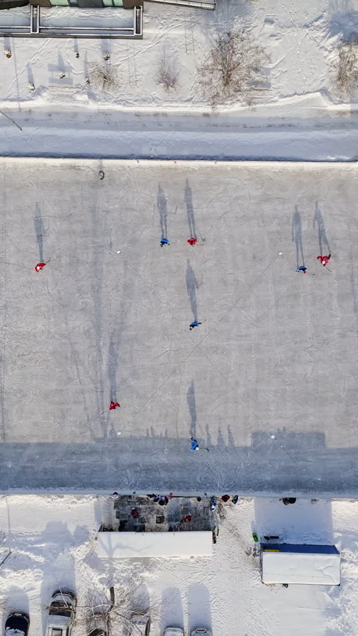 Top down drone shot above ice hockey game at a outdoor rink, sunny, winter day