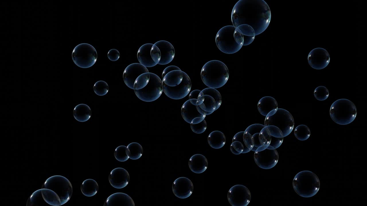 Soap bubbles fly up slow on black background