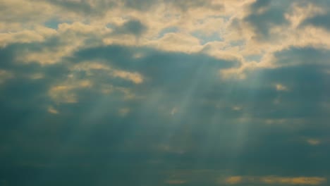 sunlight beams burst from the clouds on a blue cloudy sky