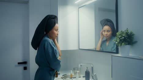 woman checking her face in the bathroom mirror