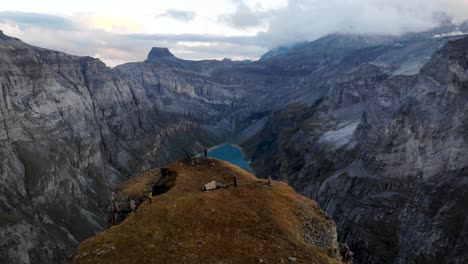 aerial flyover above a viewpoint of limmernsee in glarus, switzerland, with hikers enjoying the view of the swiss alps cliffs, landscape and lake from their camping spot