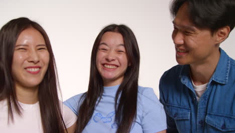 색 스튜디오 배경 앞의 젊은 친구 그룹이 사진 부스 스타일의 초상화를 위해 포즈를 취하고 있습니다.