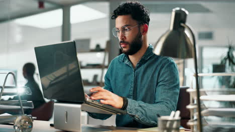man working on laptop at desk in office