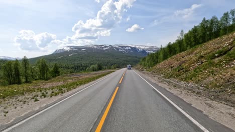 There-is-a-motorhome-travel-RV-with-travelers-on-the-way.-Driving-a-Car-on-a-Road-in-Norway-at-dawn.-Point-of-view-driving.-Family-vacation-travel-RV,-holiday-trip-in-motorhome,-Caravan-car-Vacation.