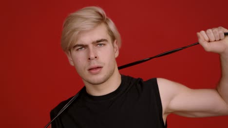 man with blonde hair and black shirt against red background