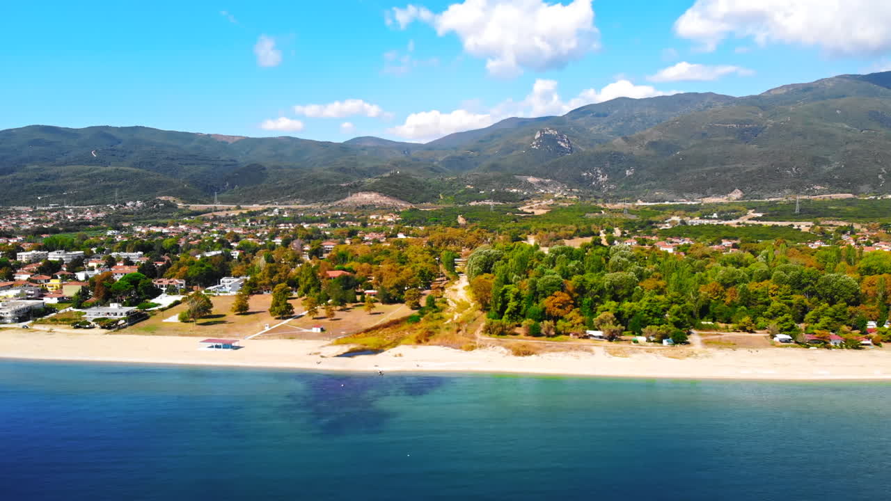 Panorama of the Asprovalta with multiple buildings and greenery, green hills on the background. Aegean sea coast. Sunny day. Greece