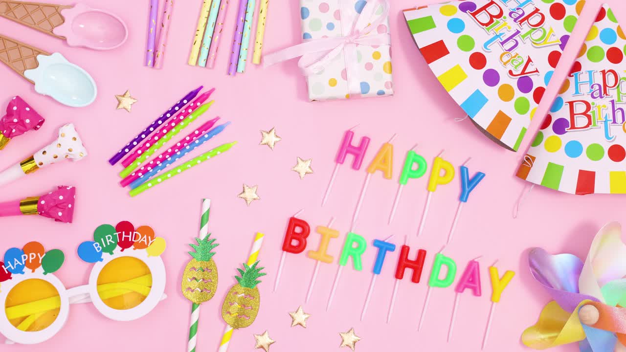 Birthday party accessories and Happy birthday candles appear on pastel pink theme. Stop motion