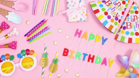 birthday party accessories and happy birthday candles appear on pastel pink theme. stop motion