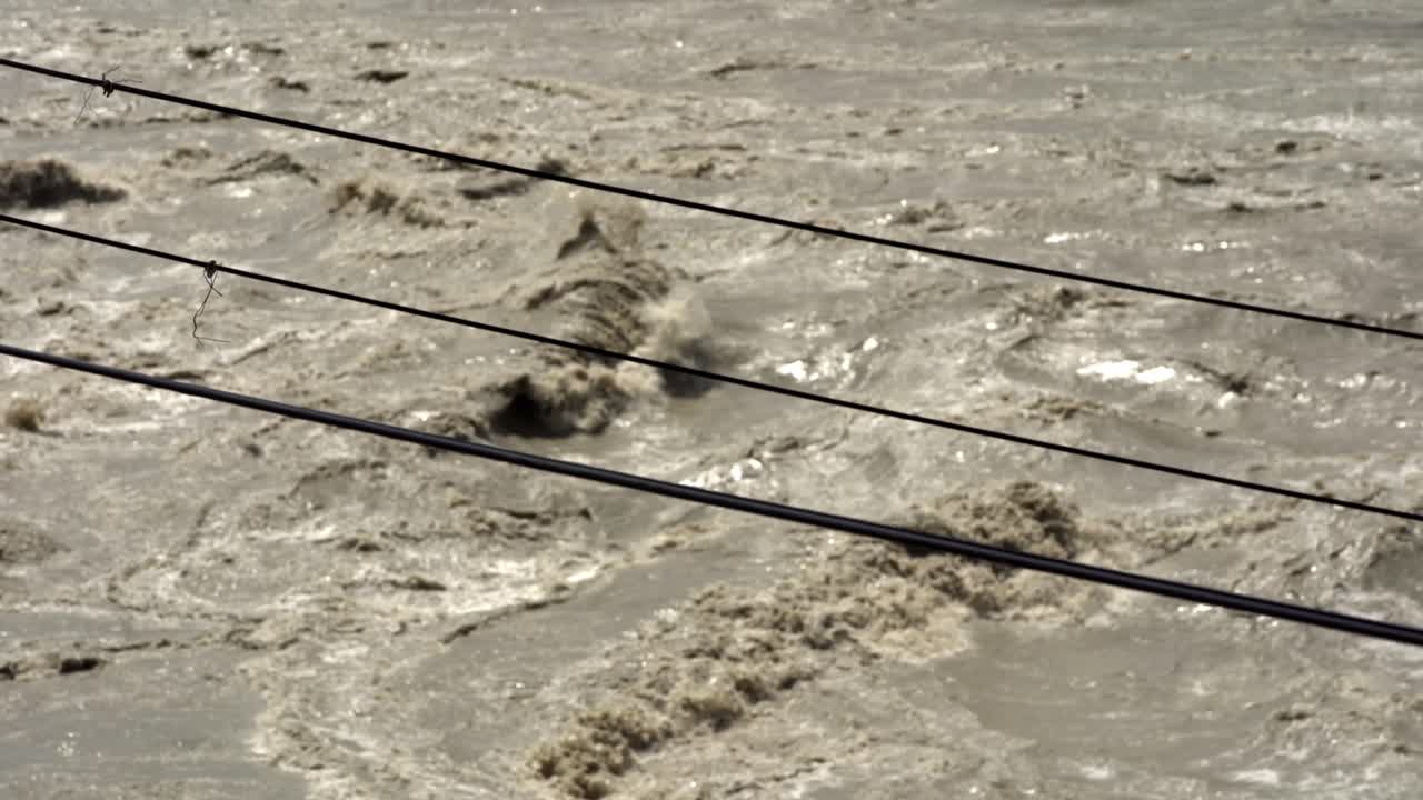 Polluted river water moving fast, high flow rate after rain, muddy agitated water