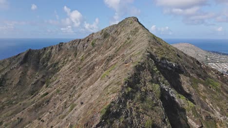 Aerial-view-of-steep-mountain-ridge-with-blue-sky-and-clouds