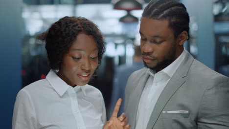 Afro colleagues having discussion in office. African couple looking tablet