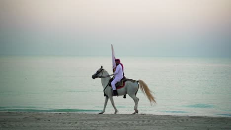 a knight riding a horse walking and holding qatar flag near the sea