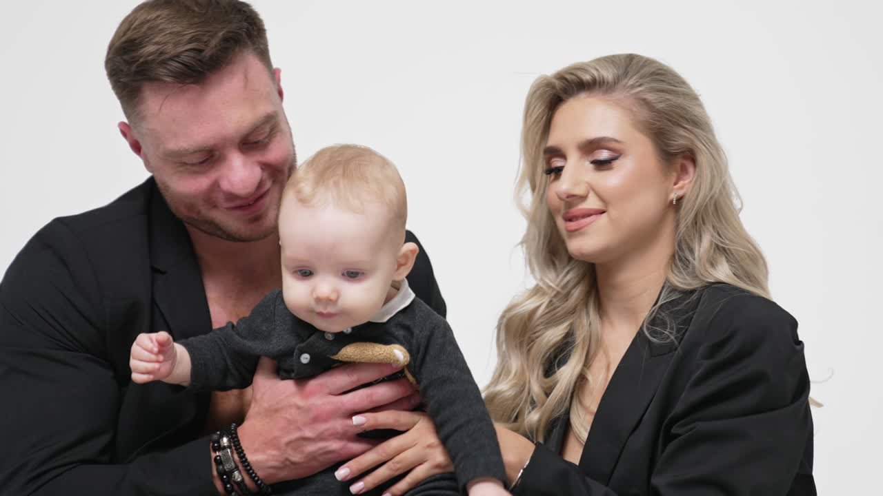Loving Caucasian parent hold their adorable baby boy. Happy parenting concept. Studio footage at white backdrop.