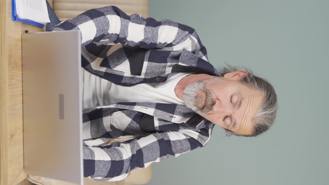 video vertical de un anciano cansado en la computadora portátil.