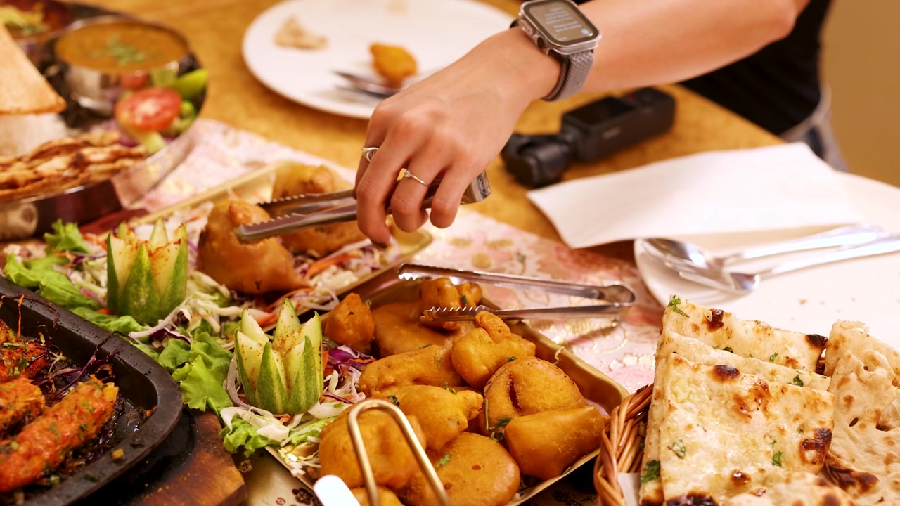 Vista dall'alto di mani che servono antipasti tradizionali indiani durante un pasto vario al ristorante