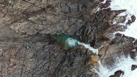 Aerial:-coasteering-tourists-jumping-into-Cape-Hillsborough-rock-pools-Australia