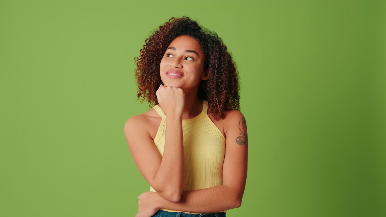 Thoughtful Young Woman Looking Up and Smiling on Green Screen
