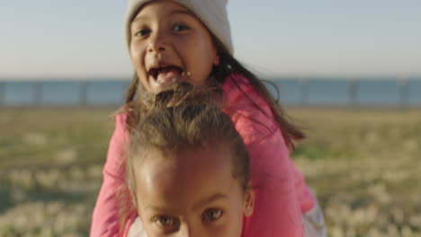 close up portrait of little mixed race girls enjoying playing games looking at camera happy cheerful seaside park