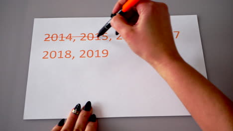 crossing out the last year's dates on a white paper, then writing the correct recent or new year 2020