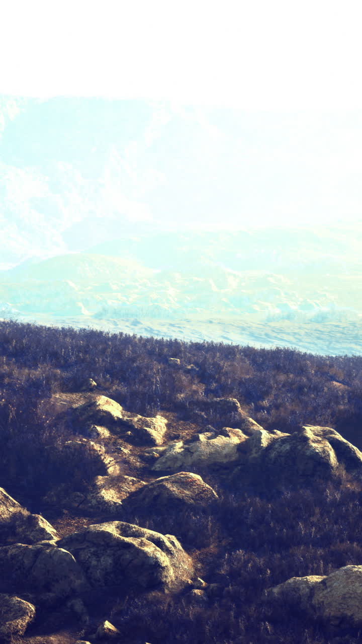 Vast mountainous landscape with rocky terrain and distant hills in sunlight