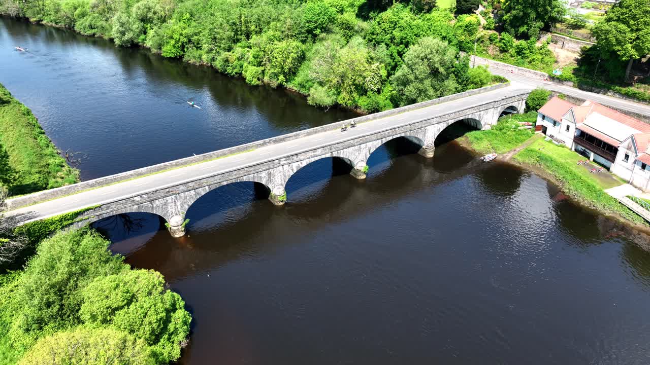 Aerial View of Rowing and Cycling on a Scenic River with a Stone Arch Bridge