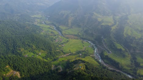 river meandering through lush green rural landscape with fog in nepal