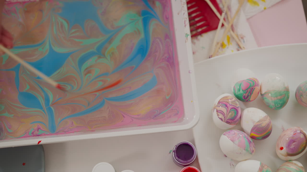 여자 는 기름진 물 에  ⁇ 은 페인트 로 추상적 인 패턴 을 그린다