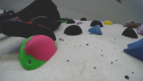 close up of an indoor climbing gym wall full of different colour holds seen from below-1