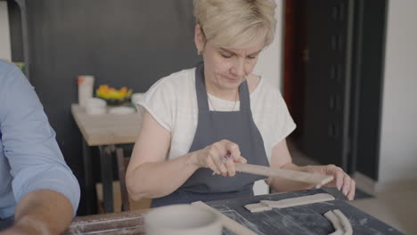 three elderly people work on a potter's wheel in slow motion