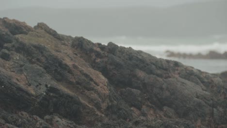 large rock on beach with waves in background