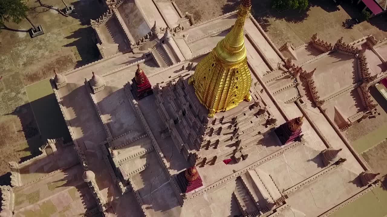 A stunning bird's-eye point of interest aerial shot of the White Temple at Ananda Temple, Bagan, Myanmar, highlighting the intricate architecture and the gleaming golden Sertok.