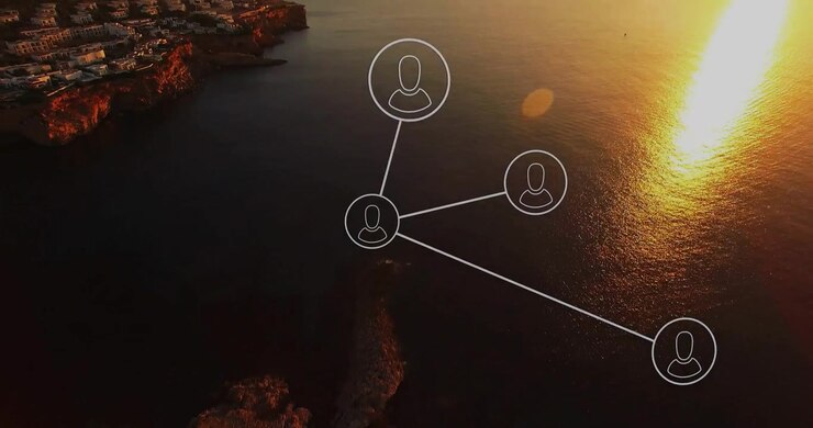 Digital network diagram floating above rocky shoreline and golden sea waters reflecting sunset