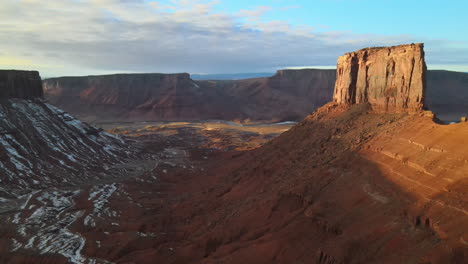 sunset aerial shot of sandstone mesas and towers outside moab, utah, in wintertime